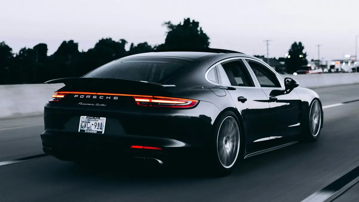 Heck einer dunklen Sportlimousine mit Endrohren auf einer Straße